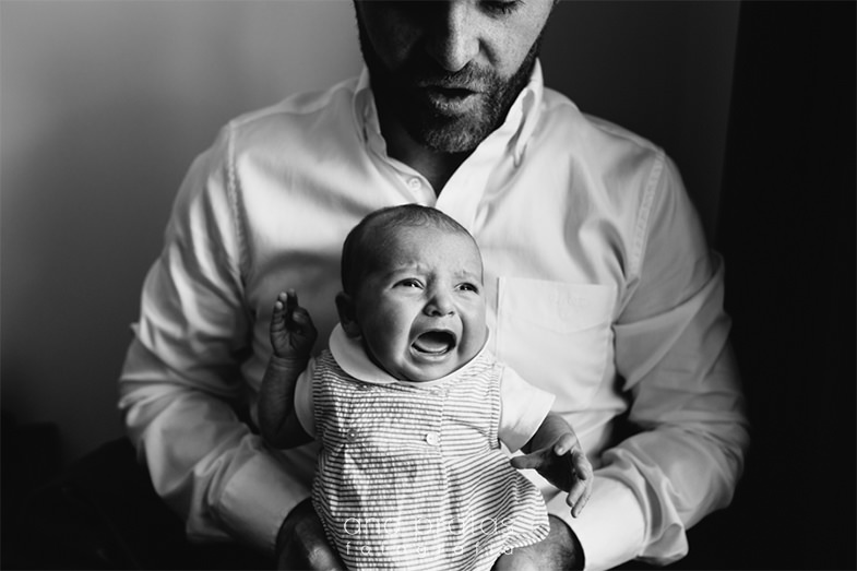bebé a chorar ao colo do pai