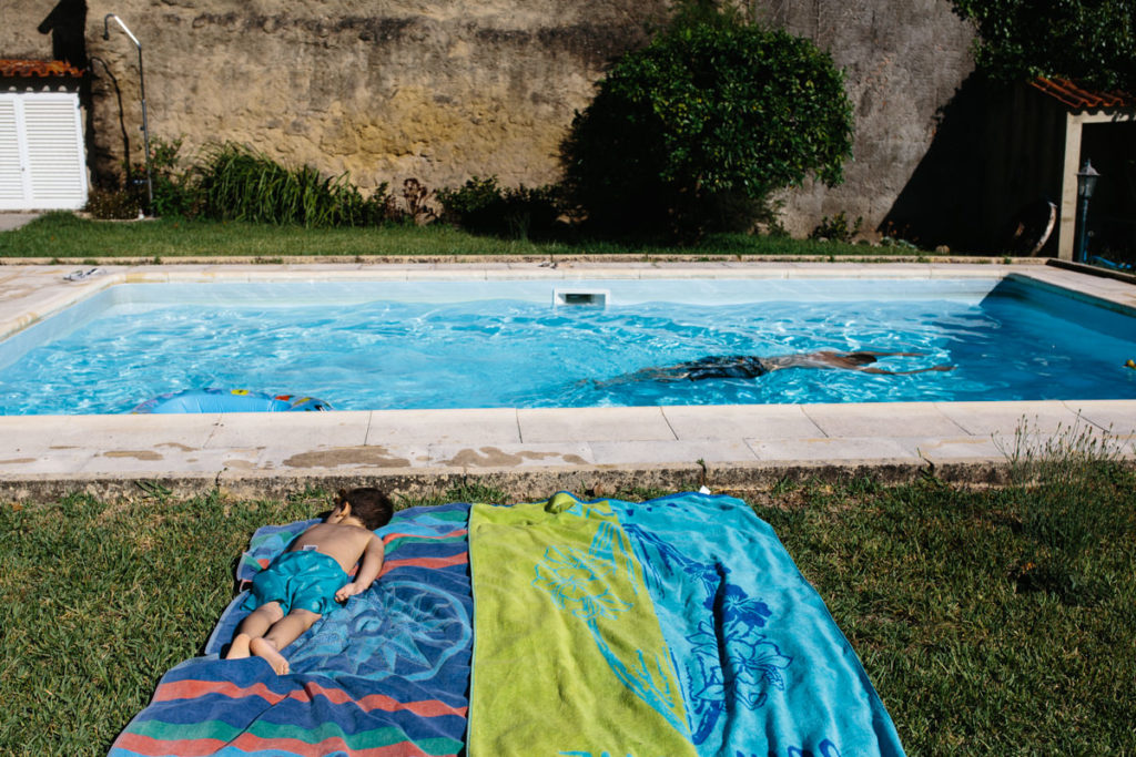 crianca deitada na toalha à beira da piscina